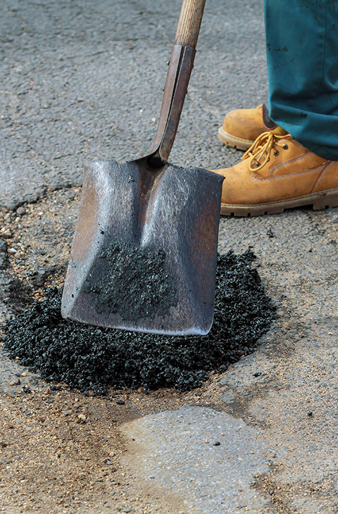 person using a shovel to apply asphalt mixture on a road repair site five tools for effective asphalt application