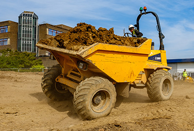 yellow dump truck transporting dirt on construction site
