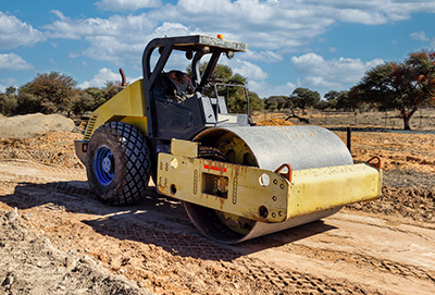 yellow road roller on construction site preparing surface for paving 2 machines working 2 jobs in progress