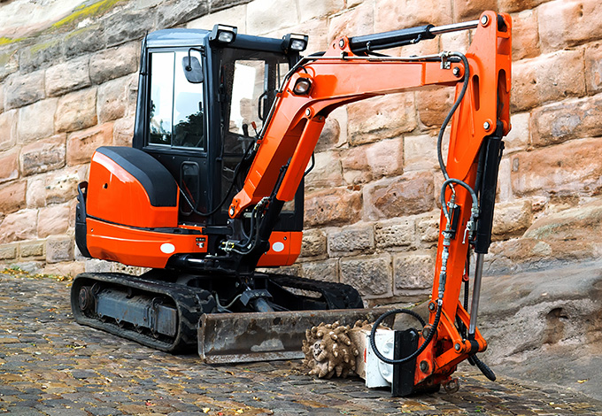 excavator with orange and black coloring parked next to a stone wall showcasing heavy machinery capabilities for construction and excavation projects and versatile applications in the field of 9 construction techniques