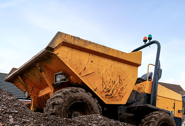 yellow dump truck on construction site with dirt and blue sky in background 4 wheel drive rugged vehicle